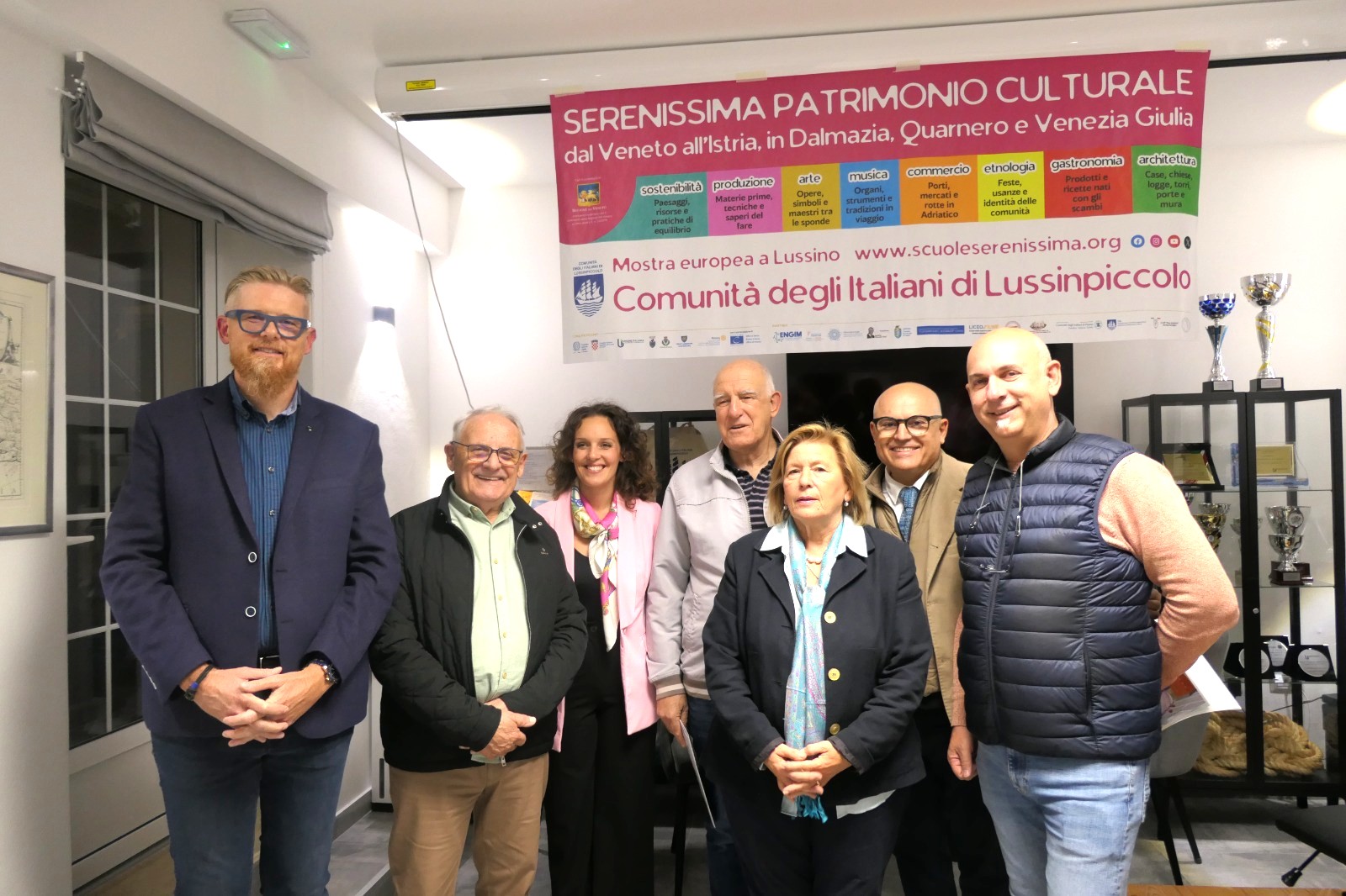 Gruppo di persone in una sala, davanti a un banner che promuove patrimoni culturali dal Veneto all'Istria in Dalmazia, Quarnero e Venezia Giulia.