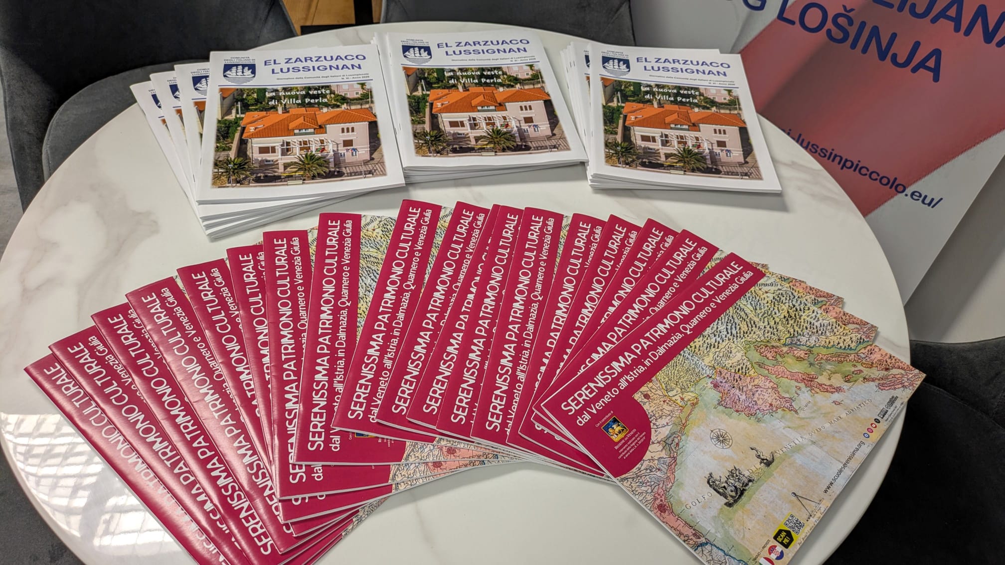 Una serie di brochure in lingua italiana su un patrimonio culturale, disposte su un tavolo, con una brochure principale che mostra una villa.